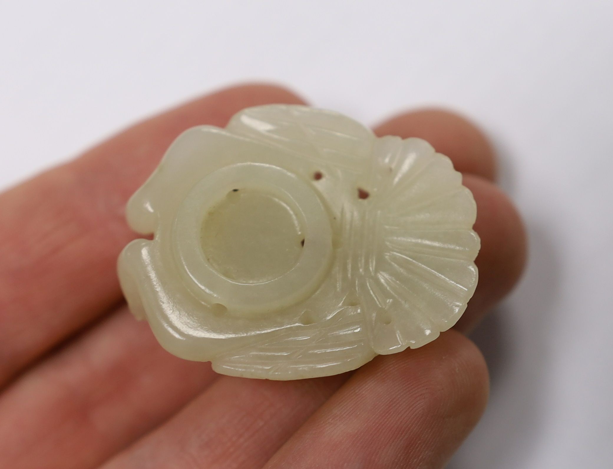A Chinese pale celadon jade mount carved as a mythical half-man half-bird creature, 18th/19th century, 3.8cm high